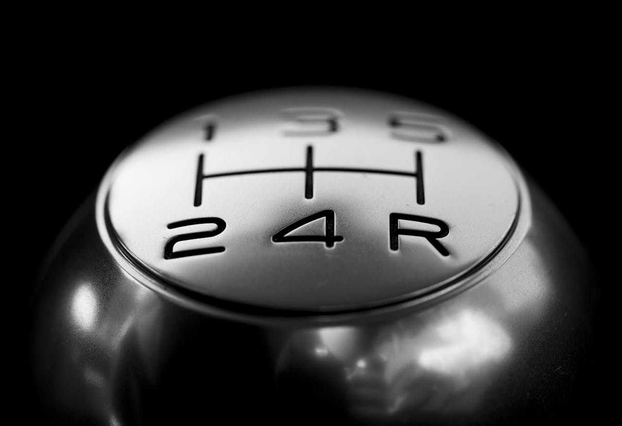 team-02 Detailed close-up of a stainless steel gear shift knob against a black background.