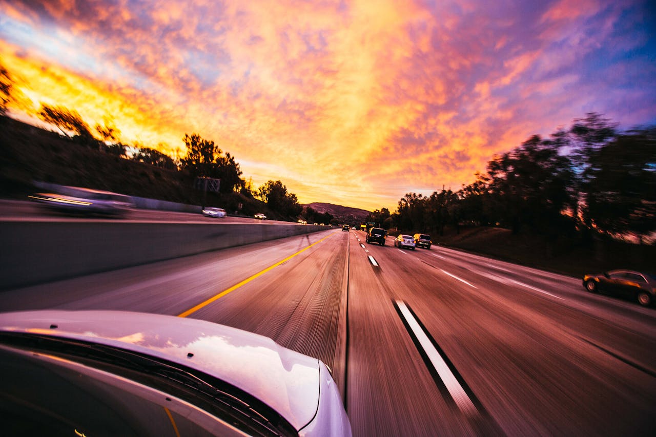who-we-are Motion blur of cars speeding on an Irvine highway at sunset with vibrant skies.